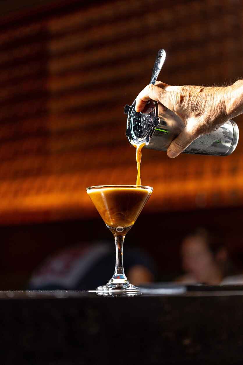 hand pouring a mixed drink at the bar